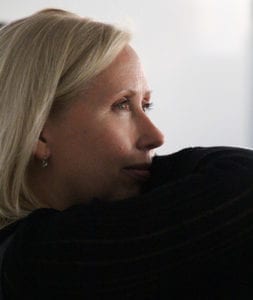 A woman sitting on the couch looking out of window.